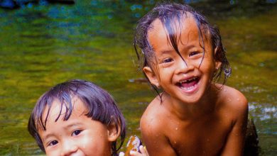 Two young children play in the river.