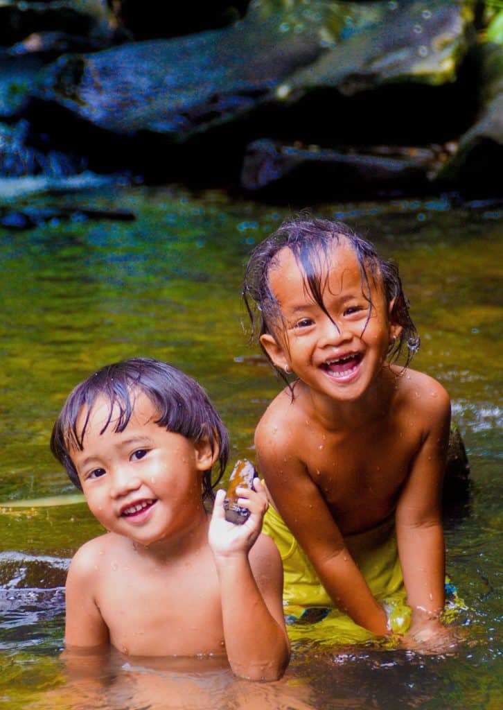 Two young children play in the river.