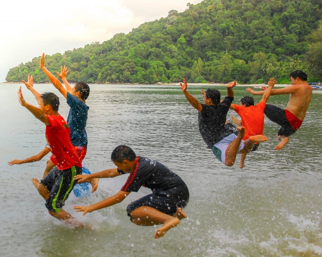 a group of boys jump into the sea.