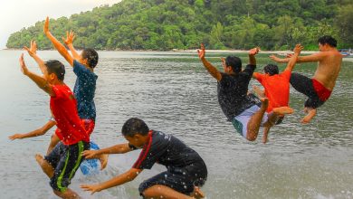 a group of boys jump into the sea.