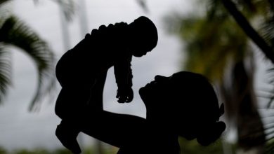 A silhouette of a mother holding up her infant child.