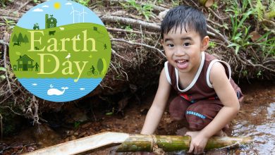 a young boy holds a bamboo stick in a river. Next to him in a the Earth Day logo.