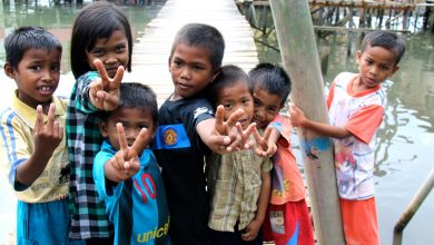 a group of children from a water village holding up the peace sign with their fingers.