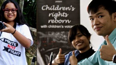 three children, one holding a camera and another two with the thumbs up sign.