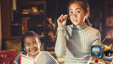 Two girls hanging out to learn. One is reading a box. Another is holding her spectacles down. At the bottom is an icon that says School TV.