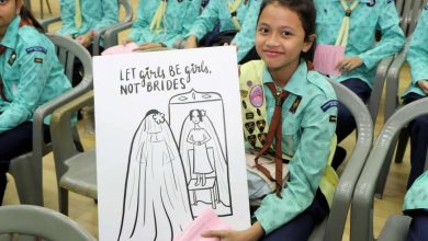 a girl guide holds up a poster to call for an end to child marriage