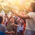 a group of happy, smiling children playing with bubbles.