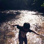 a silhouette of a boy crossing a river.