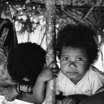 An orang asli child peers intently forward.