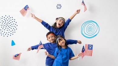 Three children, with smiles on their faces, holding out the Malaysian flag to celebrate Malaysia Human Rights.