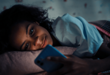 Young woman chatting on her phone while lying on the bed.