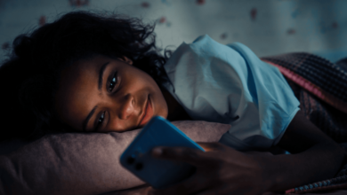 Young woman chatting on her phone while lying on the bed.